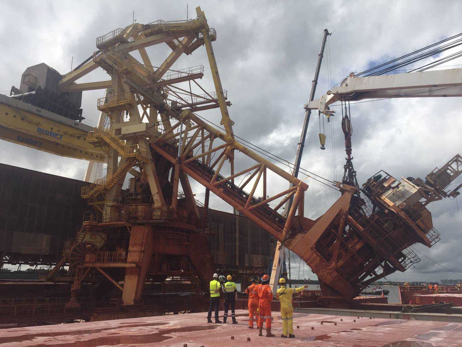 Workers are dwarfed by an enormous construction crane on the dock